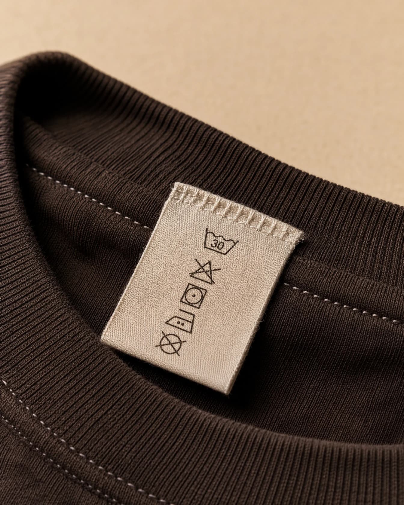 A macro view of a care label sewn into a garment collar showing wash symbols